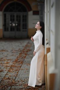 Elegant Vietnamese student in white Ao Dai reading, timeless beauty amidst classic architecture.-2
