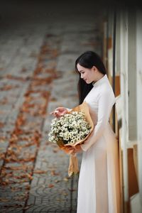 Elegant Vietnamese student in white Ao Dai reading, timeless beauty amidst classic architecture.-14