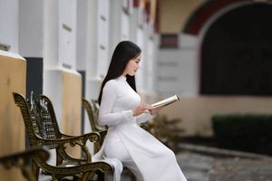 Elegant Vietnamese student in white Ao Dai reading, timeless beauty amidst classic architecture.-1