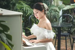 Elegant Bride Plays White Piano Amidst Lush Greenery: A Serene Wedding Moment-0
