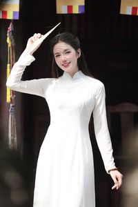 Elegant Vietnamese woman in traditional white Ao Dai, showcasing graceful beauty amidst ancient architecture.-6
