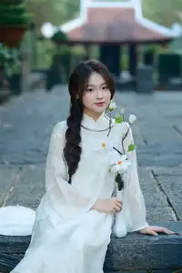 Pure Charm: White-Dressed Girl Winking Playfully with White Flowers 1000024585-1