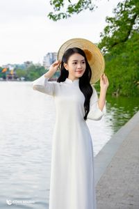 Elegant Vietnamese girl in traditional white Ao Dai by the lake, embodying cultural beauty-0
