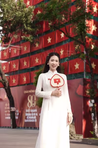 VGU No.110: Elegant White Ao Dai Amidst Red Flags, Celebrating Vietnamese Grace and Patriotism.-2