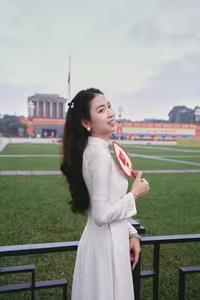 VGU No.110: Elegant White Ao Dai Amidst Red Flags, Celebrating Vietnamese Grace and Patriotism.-3