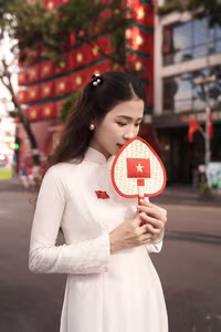 VGU No.110: Elegant White Ao Dai Amidst Red Flags, Celebrating Vietnamese Grace and Patriotism.-7