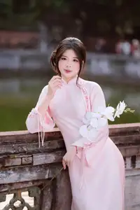 Elegant Vietnamese Beauty: Young Woman Gracefully Posing in Pink Ao Dai with White Orchids 1000026874-0