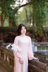 Elegant Vietnamese Beauty: Young Woman Gracefully Posing in Pink Ao Dai with White Orchids 1000026874-4