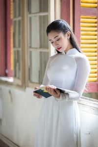 Graceful Vietnamese Girl in White Ao Dai by Window, Celebrating Traditional Beauty-0