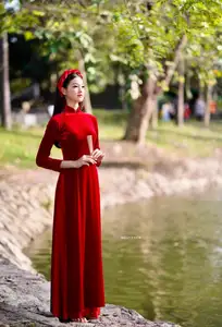 Discover the enchanting beauty of a Vietnamese woman in a traditional Red Ao Dai by the tranquil water.-1