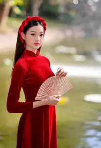 Discover the enchanting beauty of a Vietnamese woman in a traditional Red Ao Dai by the tranquil water.-2